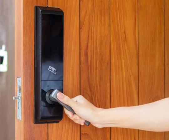 A hand turns a handle on a door with a magnetic lock